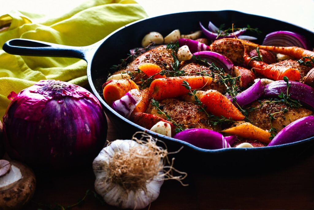 carrots, garlic, onions, and herb spicing meat iron skillet